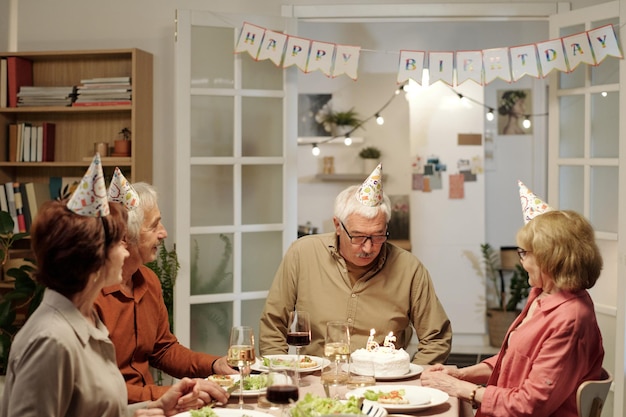 Altos hombre mirando pastel de cumpleaños con velas en forma de número sesenta y cinco