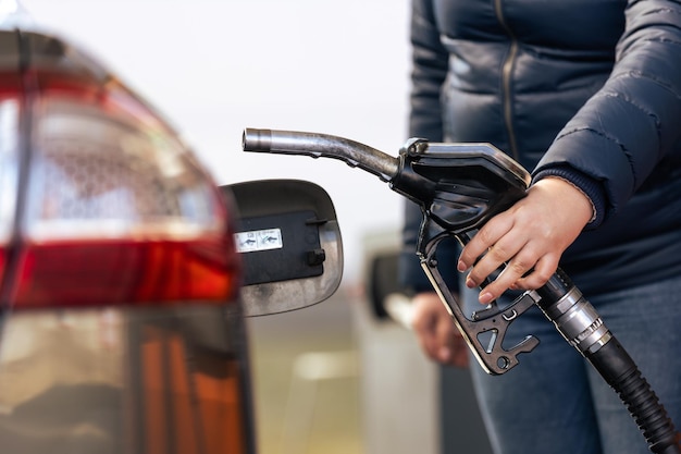 Altos precios de la gasolina y el gasóleo en la gasolinera joven repostando el coche económico