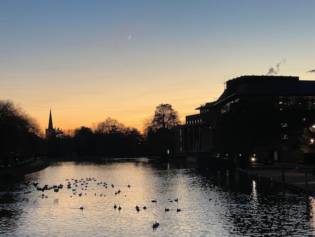 Altstadt-Landschaftssilhouette über dem Fluss mit Schwänen bei Sonnenuntergang