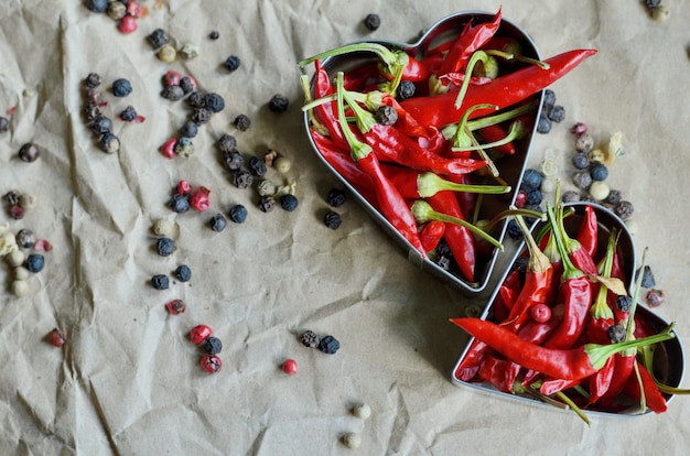 Aluminio en forma de corazón lleno de pequeños chiles sobre papel vintage