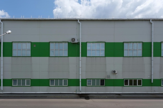 Aluminiumfassade einer Industrieanlagen-Gebäudewand mit Fenstern, Klimaanlagen und Abflussrohren