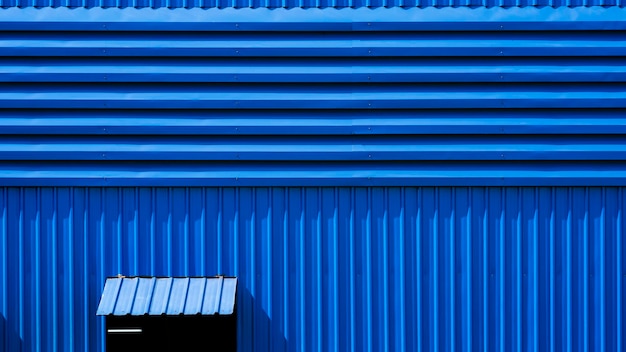 Aluminiumjalousie und geöffnetes Stahlfenster an der blauen Wand des Lagerhauses