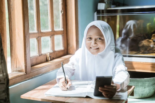 Alumna de Indonesia estudiando la tarea durante su lección en línea en casa