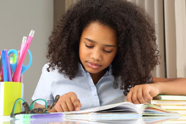 Alumna de piel oscura leyendo un libro haciendo los deberes