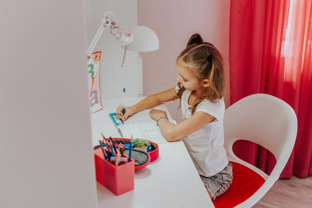 una alumna de primer grado está haciendo su tarea en casa en su habitación