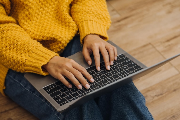 Las alumnas anotan de los libros en la biblioteca de chicas asiáticas sentadas en un sofá usando una computadora portátil y una tableta para buscar información en línea en la sala de estar