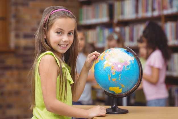 Alumno en la biblioteca apuntando al mundo