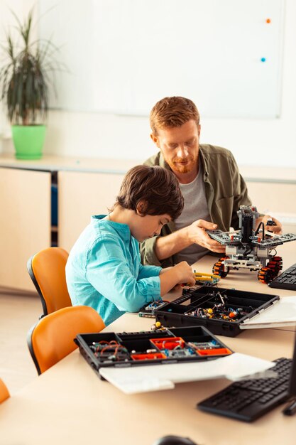 Foto alumno construyendo un robot frente a su profesor