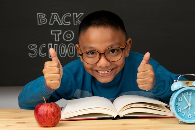 Alumno de la escuela primaria en unas gafas con la mano levantada. El niño está listo para aprender. De vuelta a la escuela.