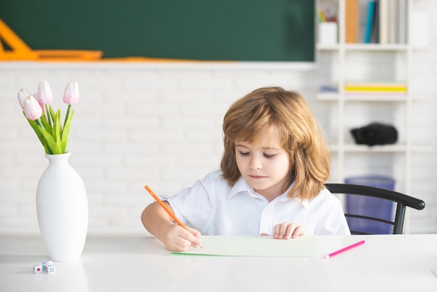 Alumno haciendo lecciones en casa Niño de la escuela escribiendo algo en el cuaderno y sentado a la mesa en el aula Alumno de primer grado