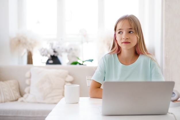 Alumno de niña feliz usando laptop en casa