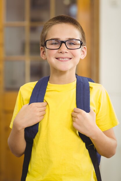 Alumno sonriente con mochila en un aula