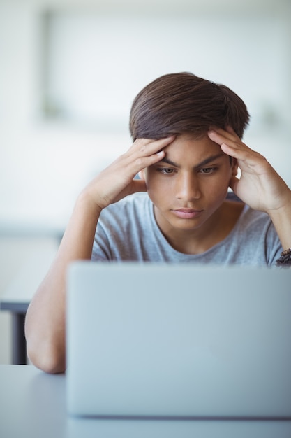 Alumno tenso mirando portátil en el aula