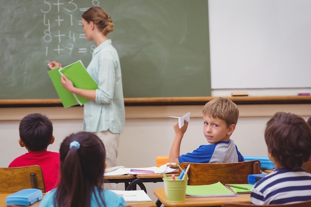 Alumno travieso a punto de lanzar avión de papel en clase