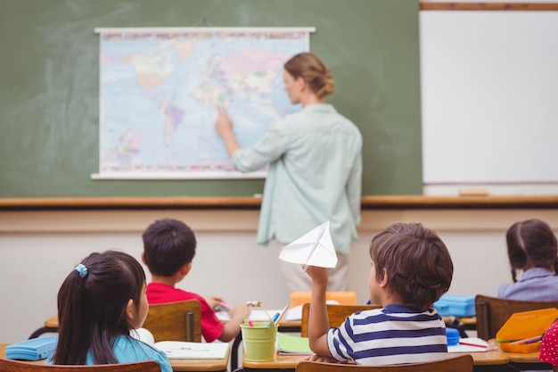 Alumno travieso a punto de lanzar avión de papel en clase