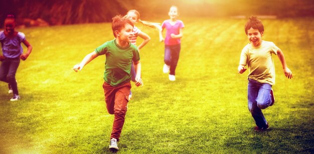 Alumnos corriendo en campo de hierba en el campus de la escuela primaria