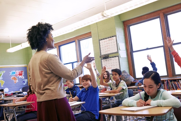 Alumnos docentes y aulas con manos para respuestas a preguntas o preguntas frecuentes de niños participativos Feliz educadora enseñando a niños entusiastas para aprender educación o desarrollarse en clase