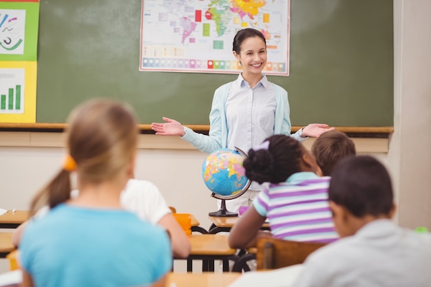 Alumnos escuchando a su maestra en la pizarra