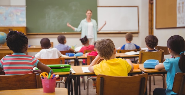 Alumnos escuchando a su profesor en la pizarra.
