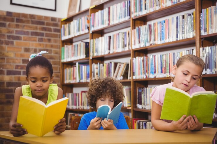 Foto alumnos felices leyendo un libro de la biblioteca