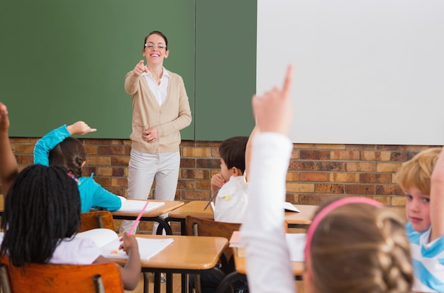 Alumnos levantando la mano durante la clase en la escuela primaria