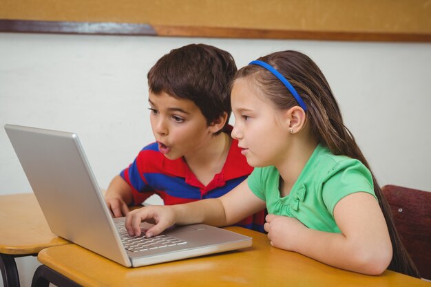 Alumnos que usan una computadora portátil en clase