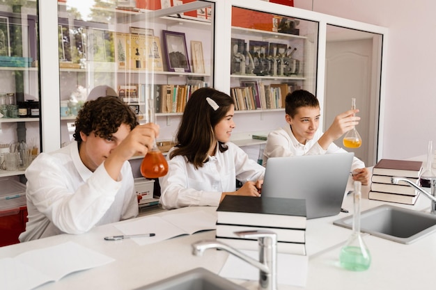 Alumnos sosteniendo matraces con líquido para experimentos en laboratorio Concepto de educación Grupo de alumnos que estudian la lección de química en la escuela