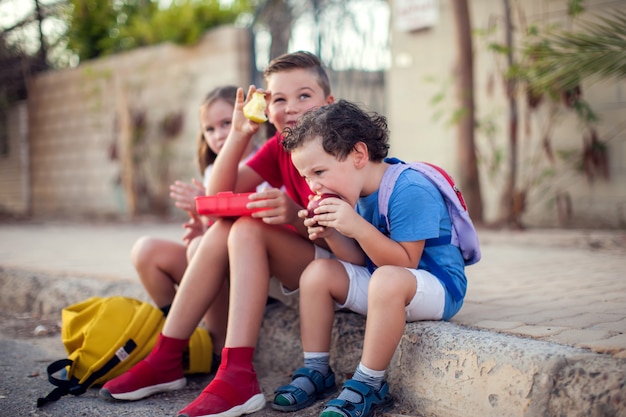 Alumnos tomando un aperitivo al aire libre. Concepto de niños, educación y nutrición.