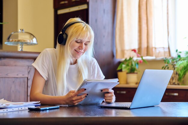 Aluna adolescente em fones de ouvido estudando em casa usando um laptop
