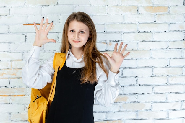 Aluna adorável fica em fundo branco e mostrando as mãos