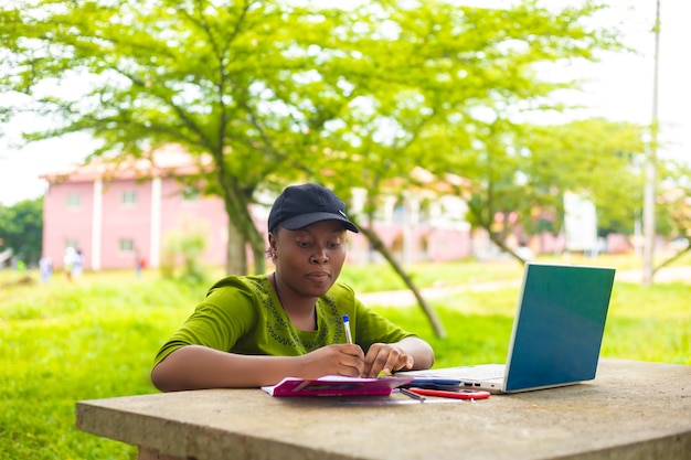 Aluna africana bonita se sentindo animada enquanto trabalhava em sua tarefa no campus