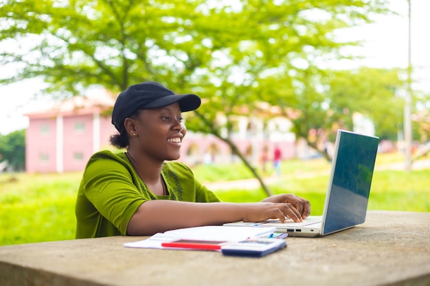 Aluna africana bonita se sentindo animada enquanto trabalhava em sua tarefa no campus
