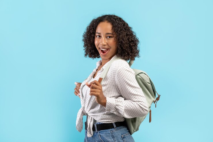 Foto aluna afro-americana animada com mochila gritando uau sobre o fundo azul do estúdio