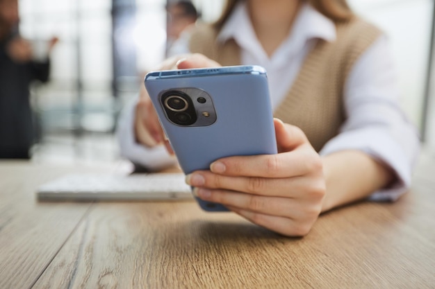 Aluna alegre sentada à mesa com um telefone celular recebeu uma mensagem de um amigo