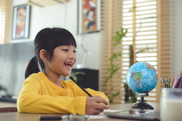 Aluna asiática estuda aula de aprendizado on-line, professor de zoom de chamada de vídeo on-line, garota feliz aprende inglês on-line com laptop em casa. Novo normal. Coronavírus Covid-19. Distanciamento social. fique em casa