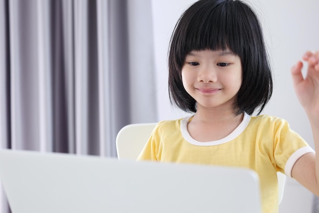 Aluna asiática estuda on-line usando o laptop em casa