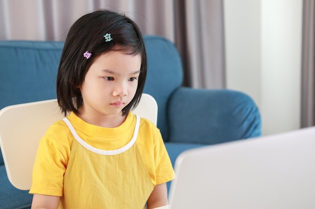 Aluna asiática estuda on-line usando o laptop em casa