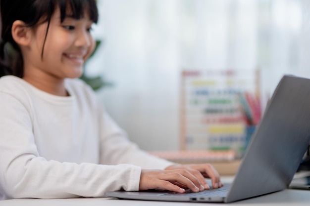 Aluna asiática fazendo lição de casa com laptop em casa crianças usam gadgets para estudar educação e ensino a distância para crianças educação em casa durante a quarentena fique em casa