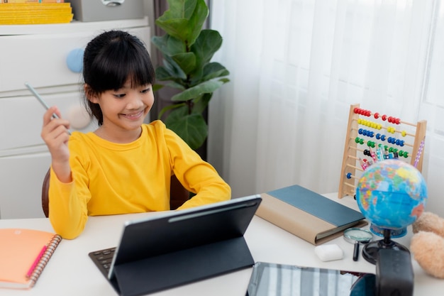 Aluna asiática fazendo lição de casa com tablet digital em casa Crianças usam gadgets para estudar Educação e ensino à distância para crianças Educação em casa durante a quarentena Fique em casa