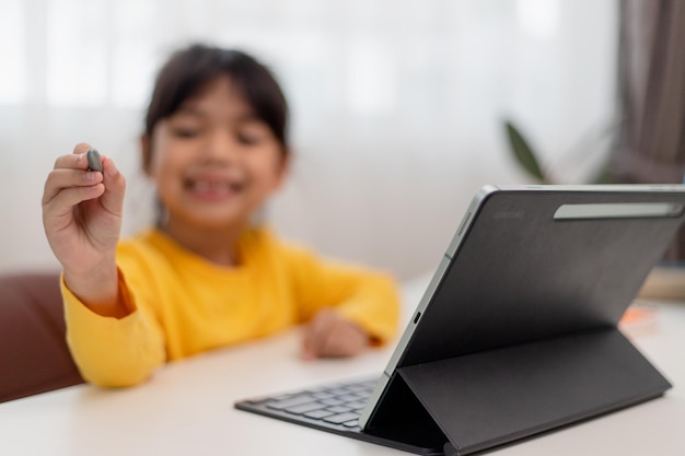Aluna asiática fazendo lição de casa com tablet digital em casa Crianças usam gadgets para estudar Educação e ensino à distância para crianças Educação em casa durante a quarentena Fique em casa