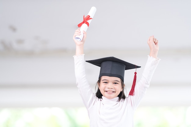 Foto aluna asiática graduada com um chapéu de formatura segurando um papel certificado enrolado