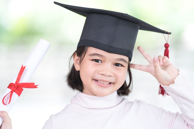 Foto aluna asiática graduada com um chapéu de formatura segurando um papel certificado enrolado