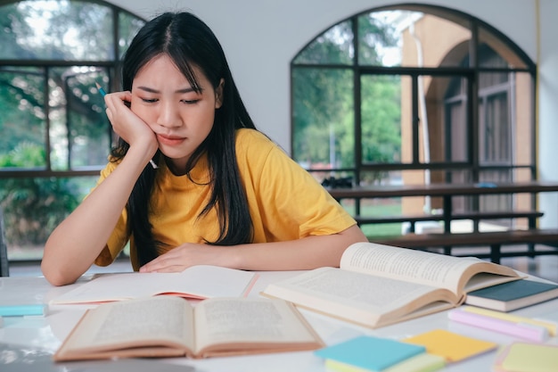 Aluna asiática séria lendo livros para preparação para exames