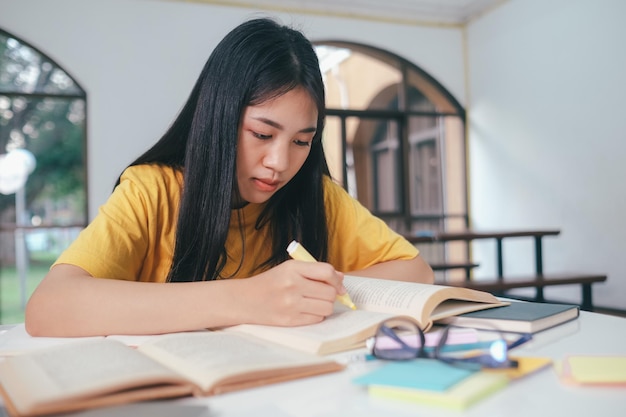 Aluna asiática séria lendo livros para preparação para exames