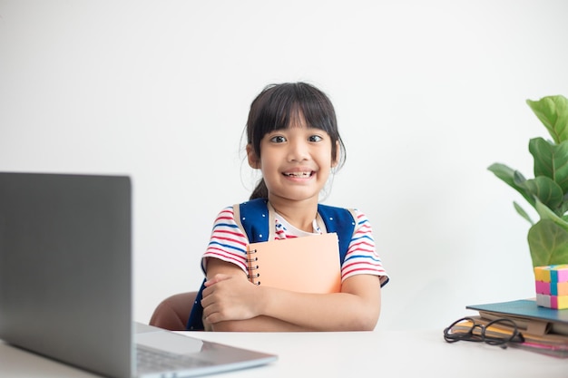 Aluna asiática usando mochila escolar e segurando livro de exercícios Retrato de uma jovem asiática felizDe volta à escola