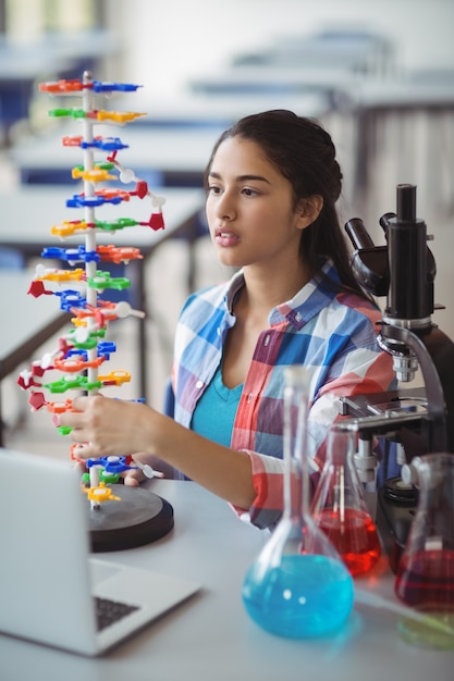 Foto aluna atenta experimentando modelo de molécula em laboratório