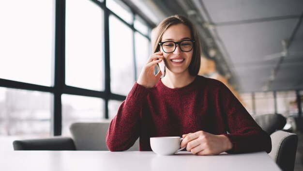 aluna atraente entre em contato com o atendimento ao cliente no celular bebendo chá