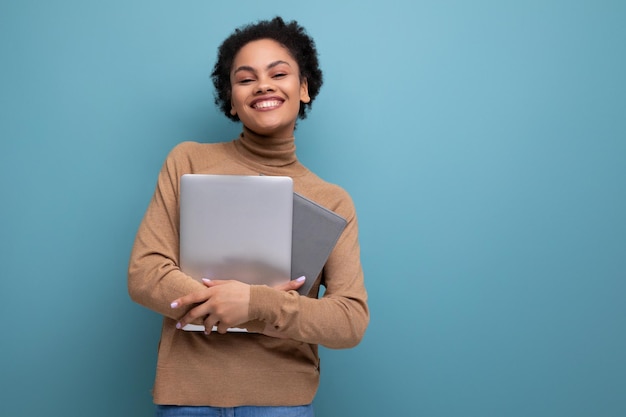 Foto aluna bem-sucedida com pele morena e cabelos fofos estudando remotamente usando laptop em