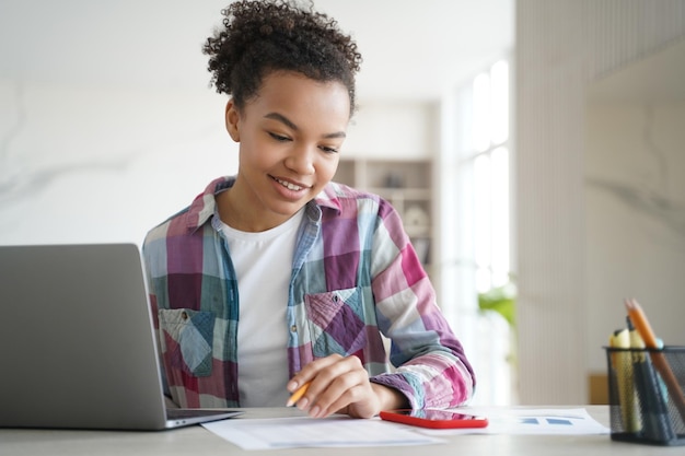 Aluna birracial aprendendo no laptop olha para o smartphone distraído do estudo Vício em gadget