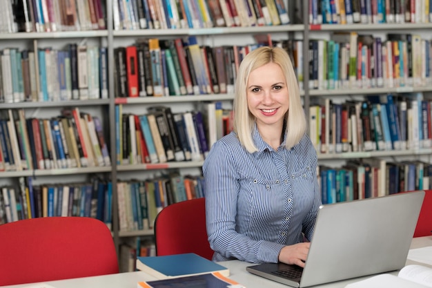 Aluna bonita com livros trabalhando em uma biblioteca do ensino médio